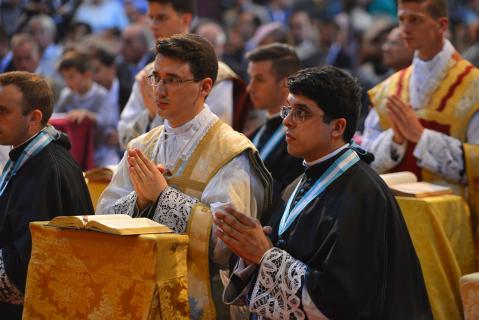Les jeunes prêtres récitent en même temps que le Pontife les prières, assistés par un prêtre
