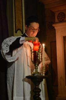 Le premier acolyte allume la lampe du Saint Sacrement