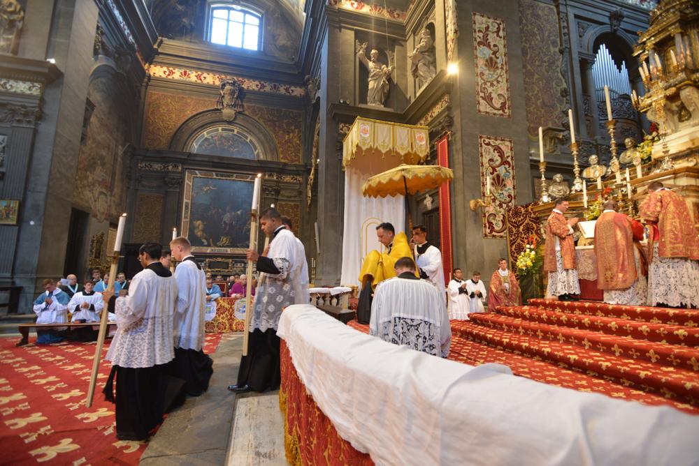 Le Saint-Sacrement, précédé des flambeaux, est porté en procession à l&rsquo;autel latéral